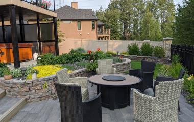 Tiered back yard with steps and Dimensional rock walls to create a fire table patio. Patio is made with Bridgewood Slabs
