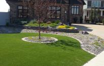 Minimal maintenance front yard with artificial turf and a rock wall foundation bed